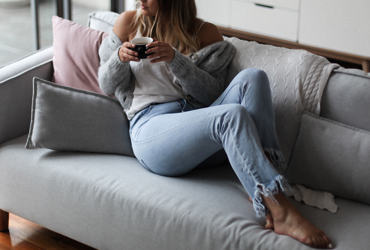 wearing frayed jeans and drinking coffee on couch